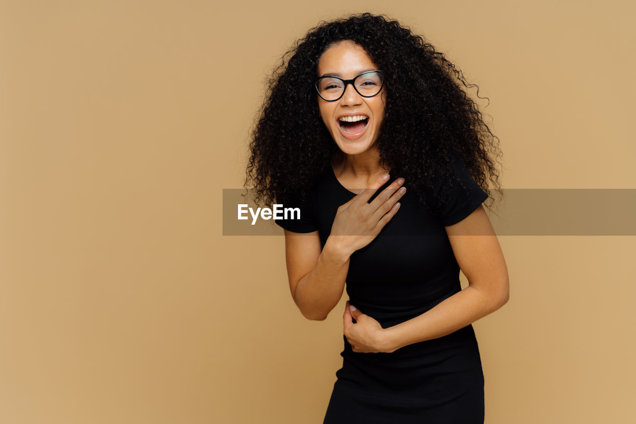 PORTRAIT OF A SMILING YOUNG WOMAN OVER GRAY BACKGROUND