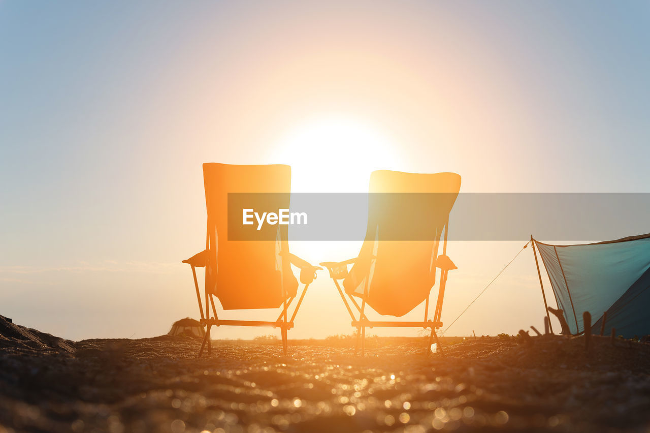 Two folding camping chairs against the backdrop of the setting sun. camping tourism. nobody