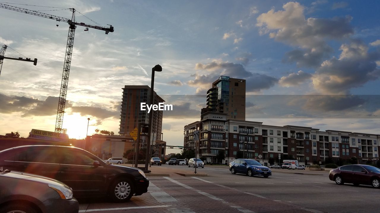 CARS ON STREET AGAINST CLOUDY SKY