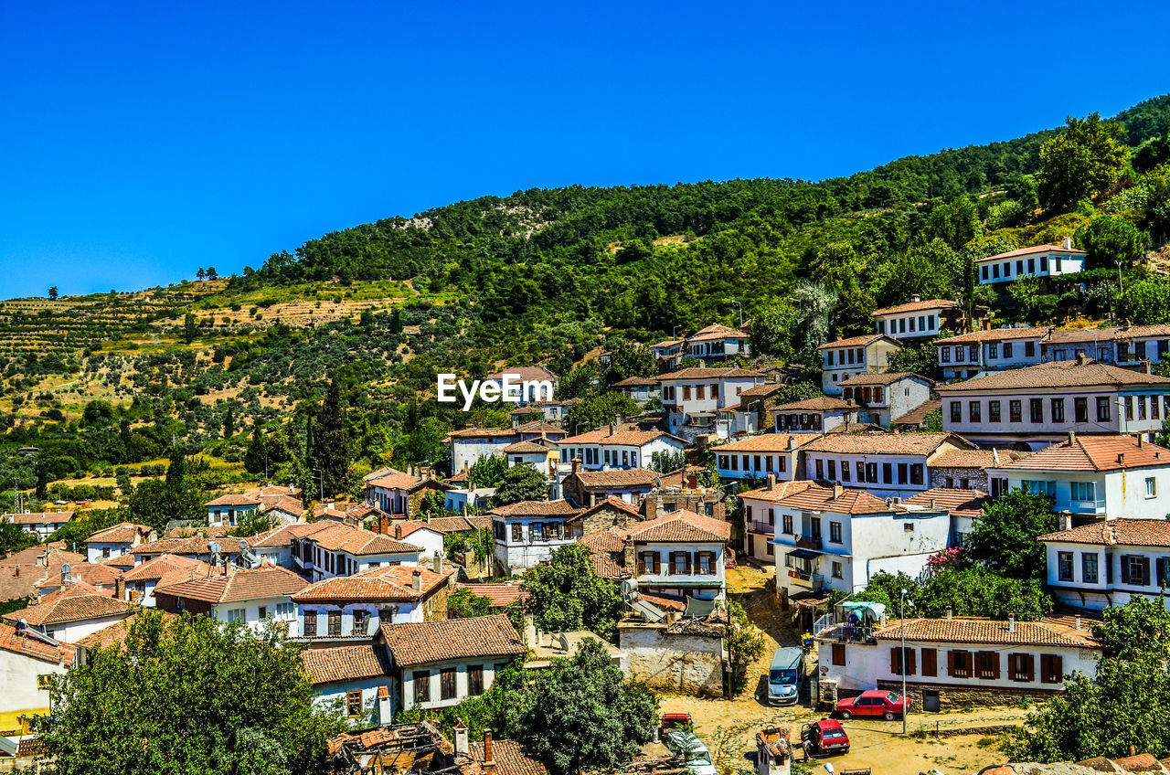 Houses on mountain against clear blue sky