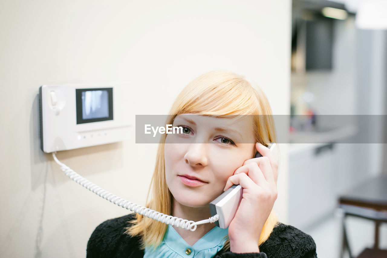 Close-up portrait of young woman talking on phone at home