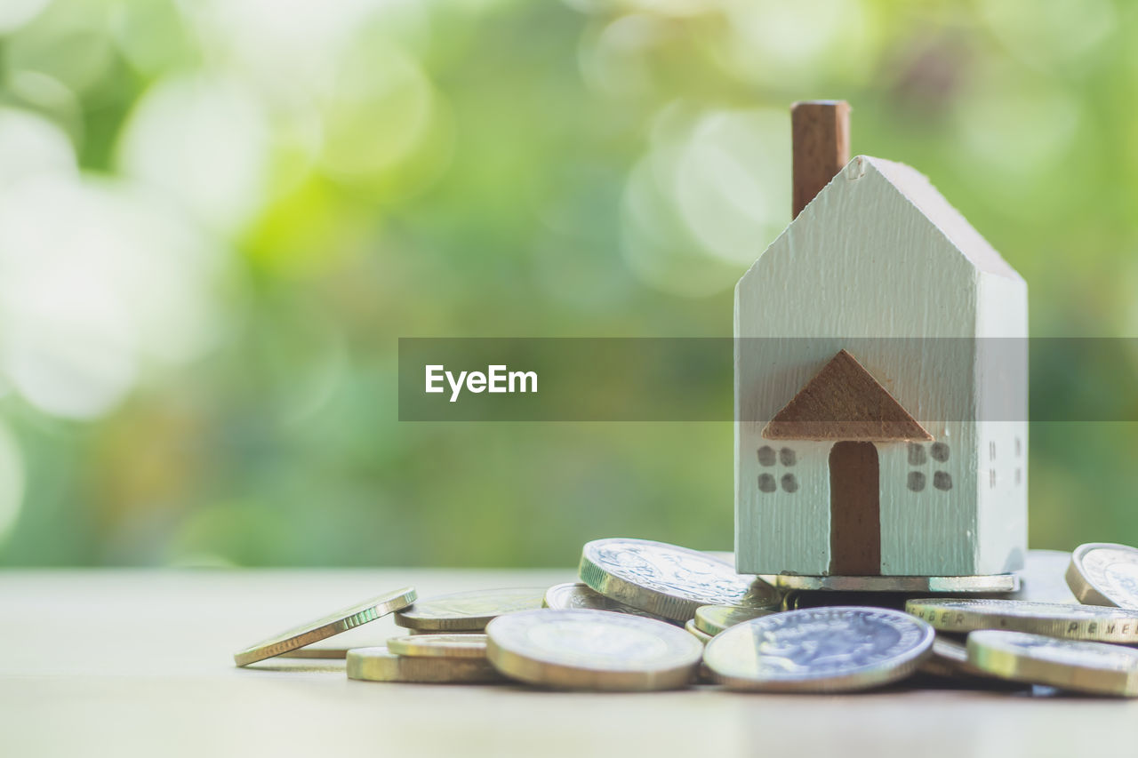 Close-up of coins and toy home on table