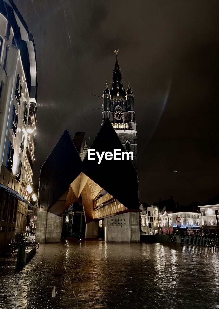 BUILDINGS BY RIVER AGAINST SKY AT NIGHT