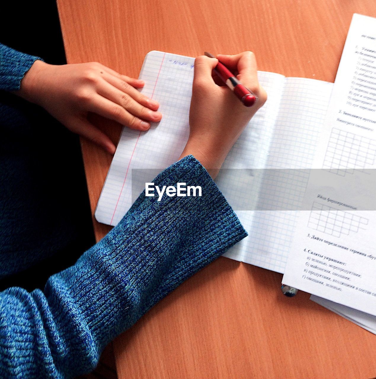 High angle view of woman writing in book on desk at home