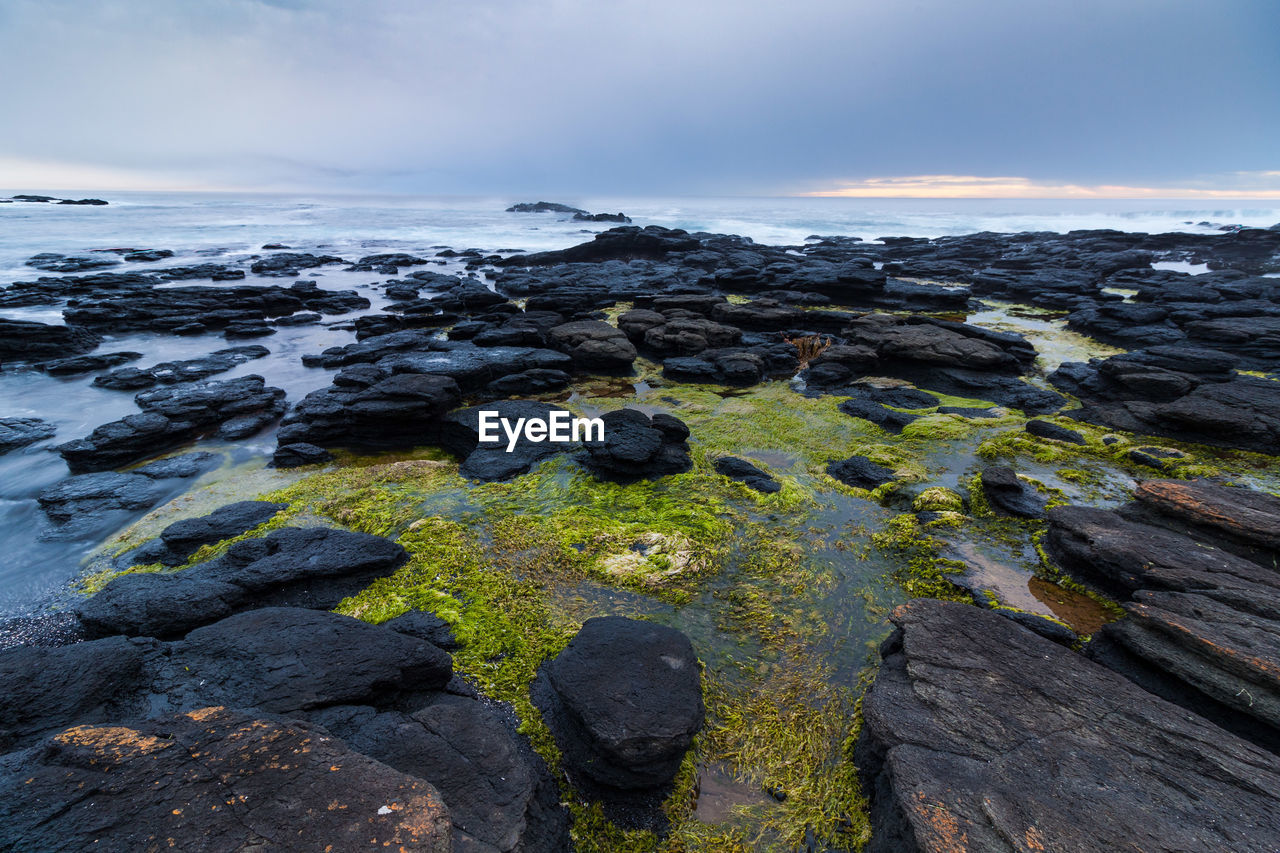 Scenic view of rocks in sea against sky