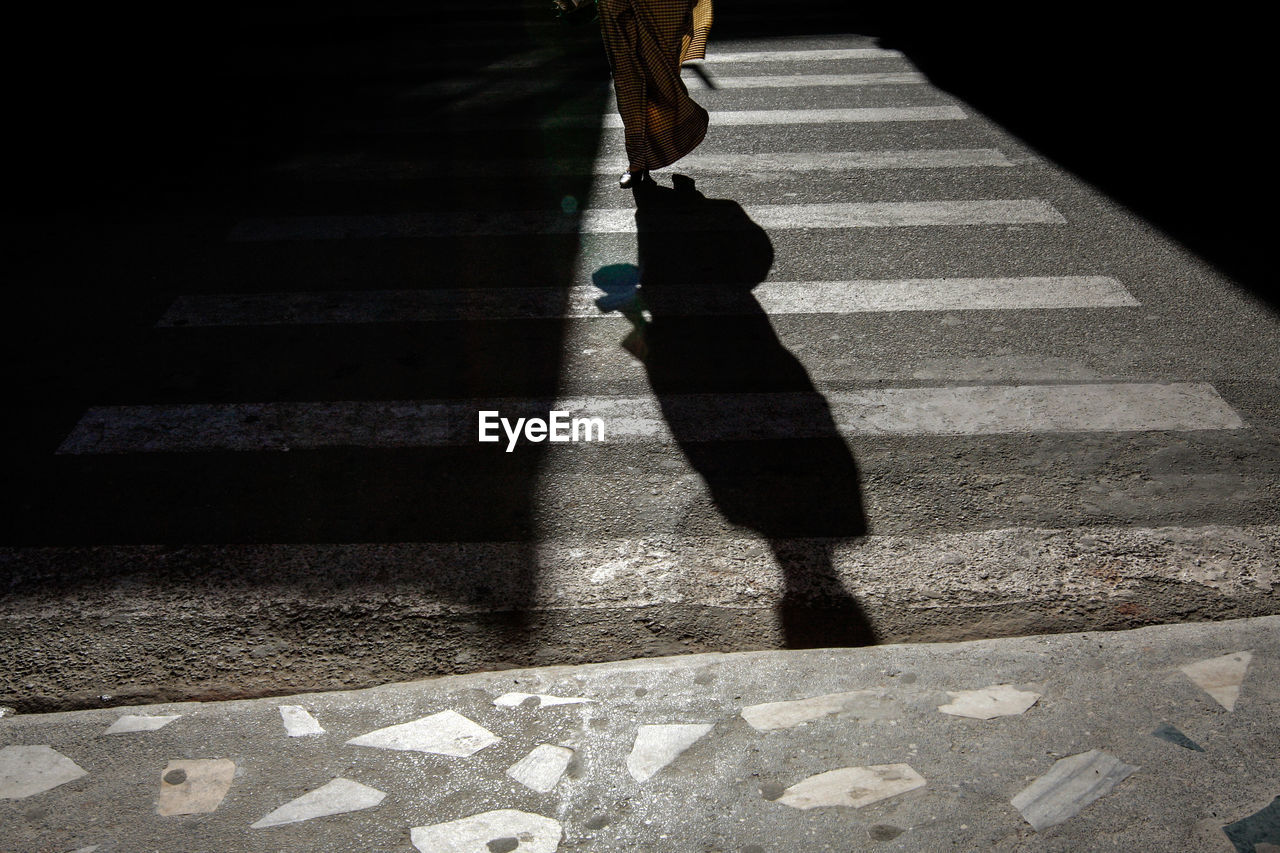 Low section of woman walking on zebra crossing