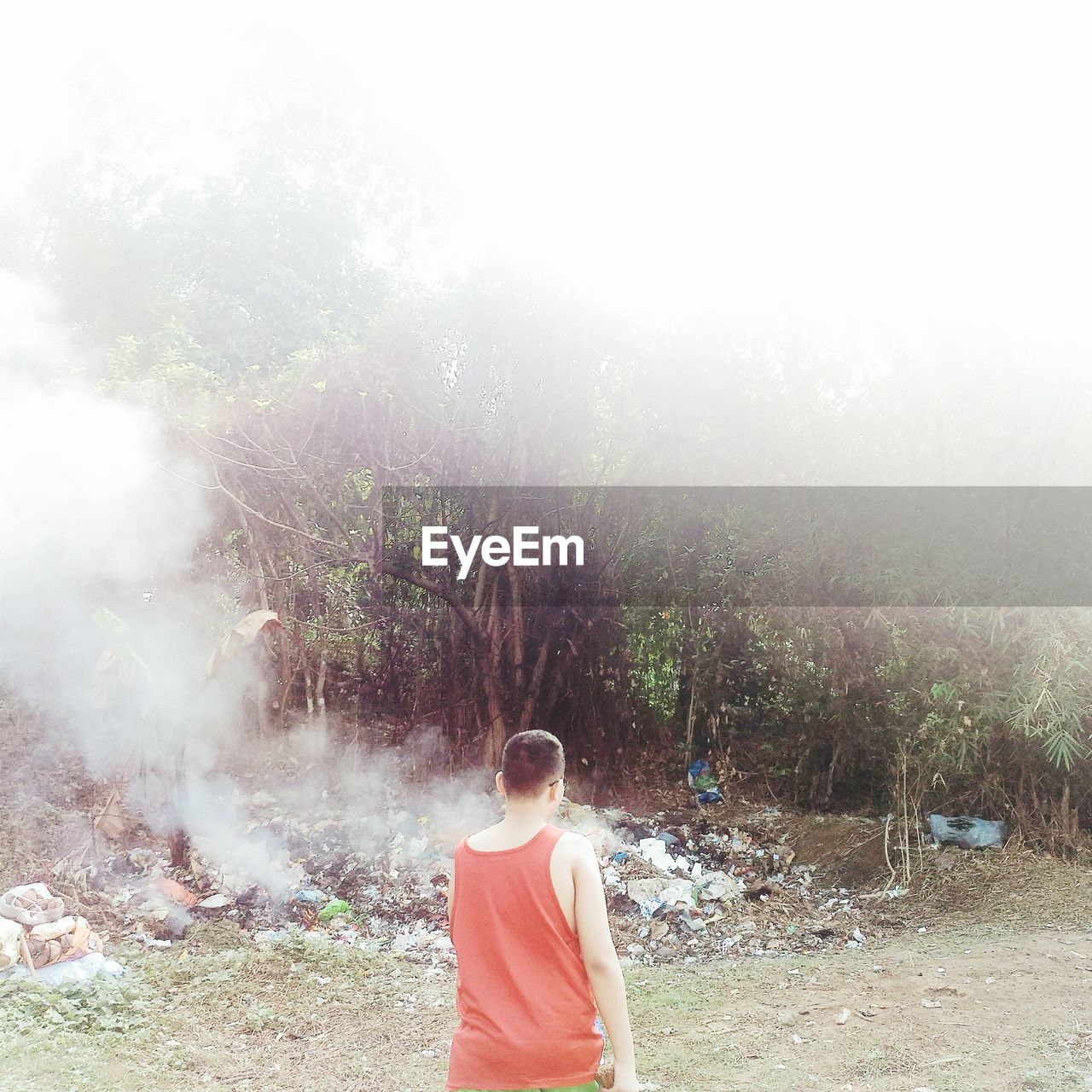 REAR VIEW OF WOMAN STANDING ON FIELD AGAINST TREES