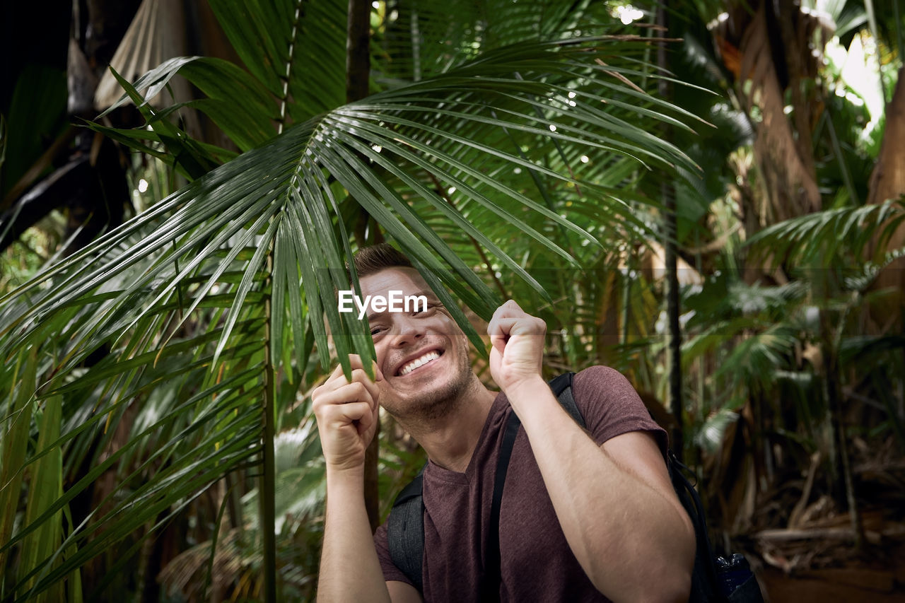 Happy man discovering jungle. funny portrait of traveler in tropical rainforest in seychelles.