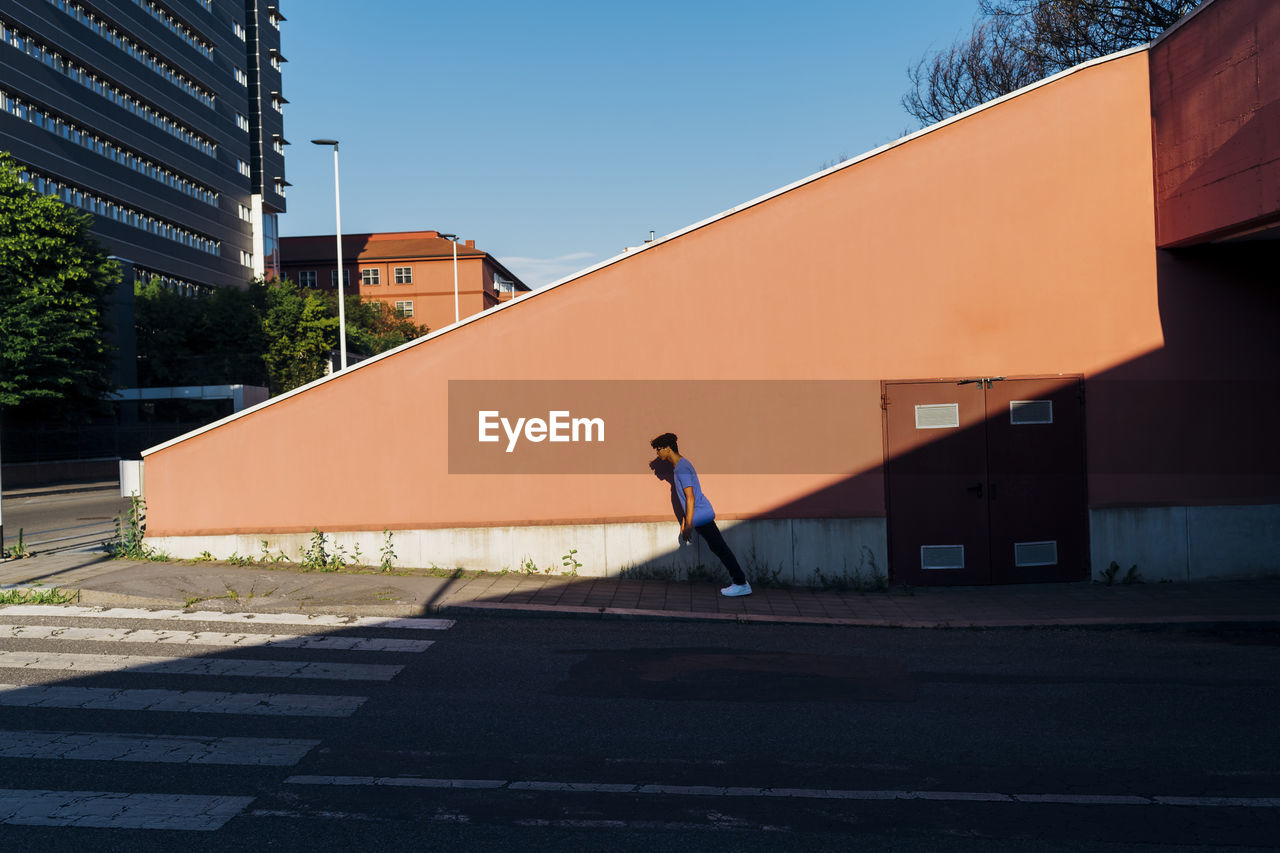 Young man leaning by wall in city