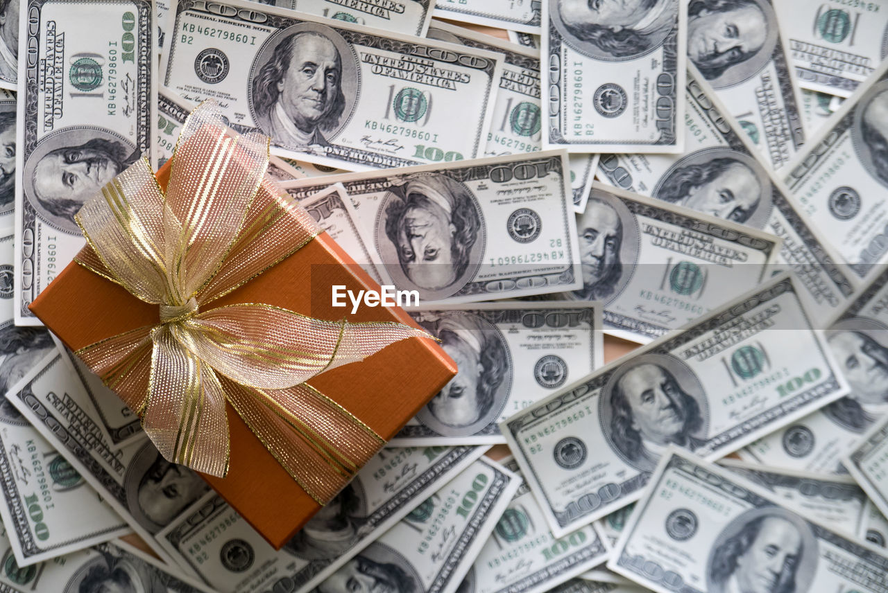 High angle view of gift box with paper currencies on table