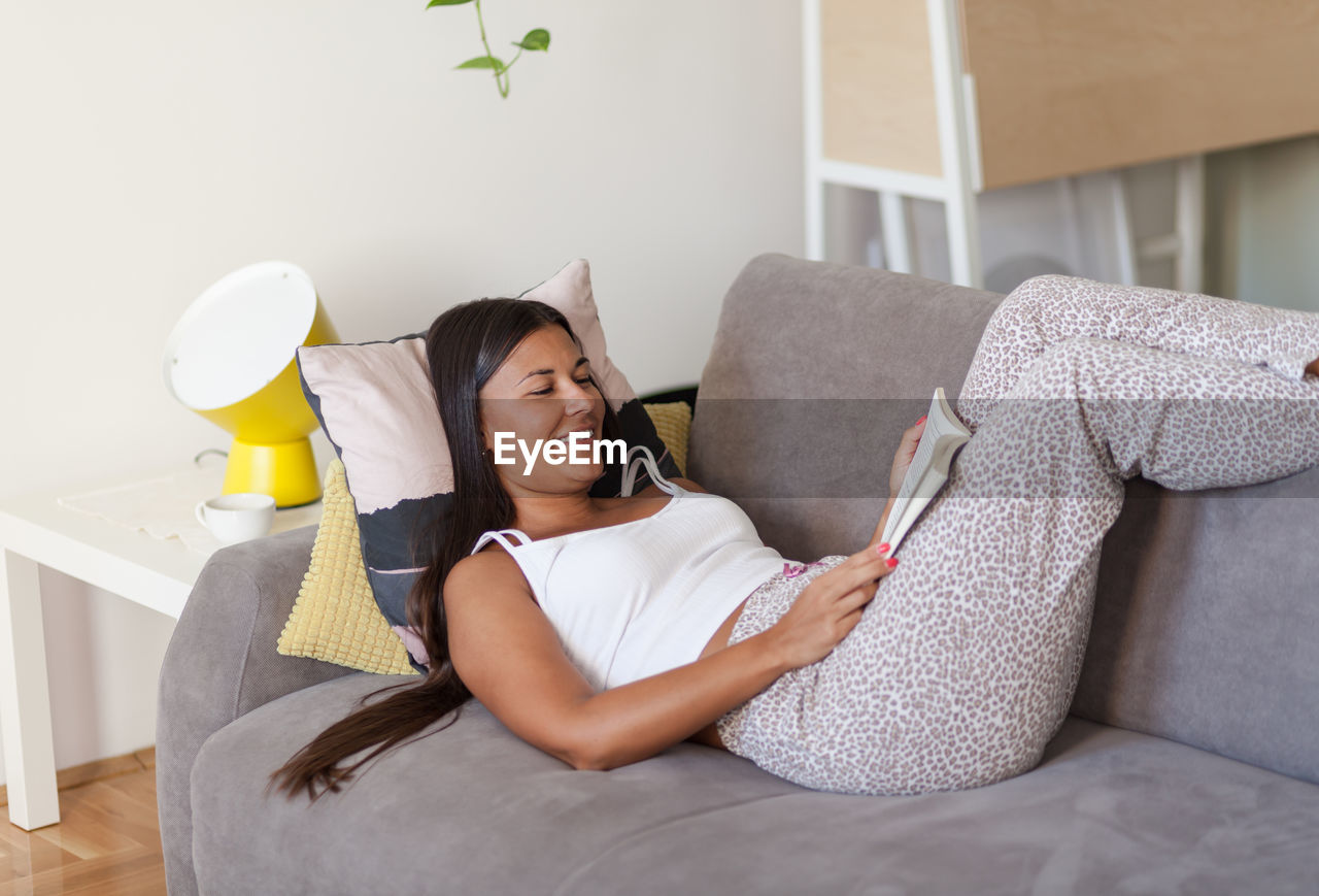 FULL LENGTH OF YOUNG WOMAN SITTING ON LAPTOP