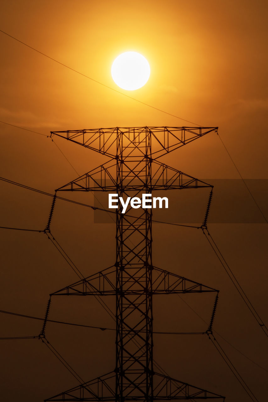 Low angle view of silhouette electricity pylon against sky during sunset