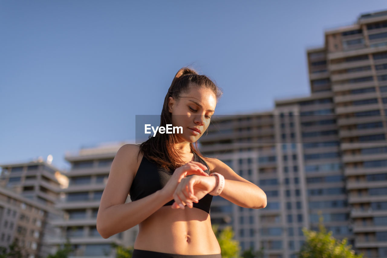 Young sportive woman using smart watch