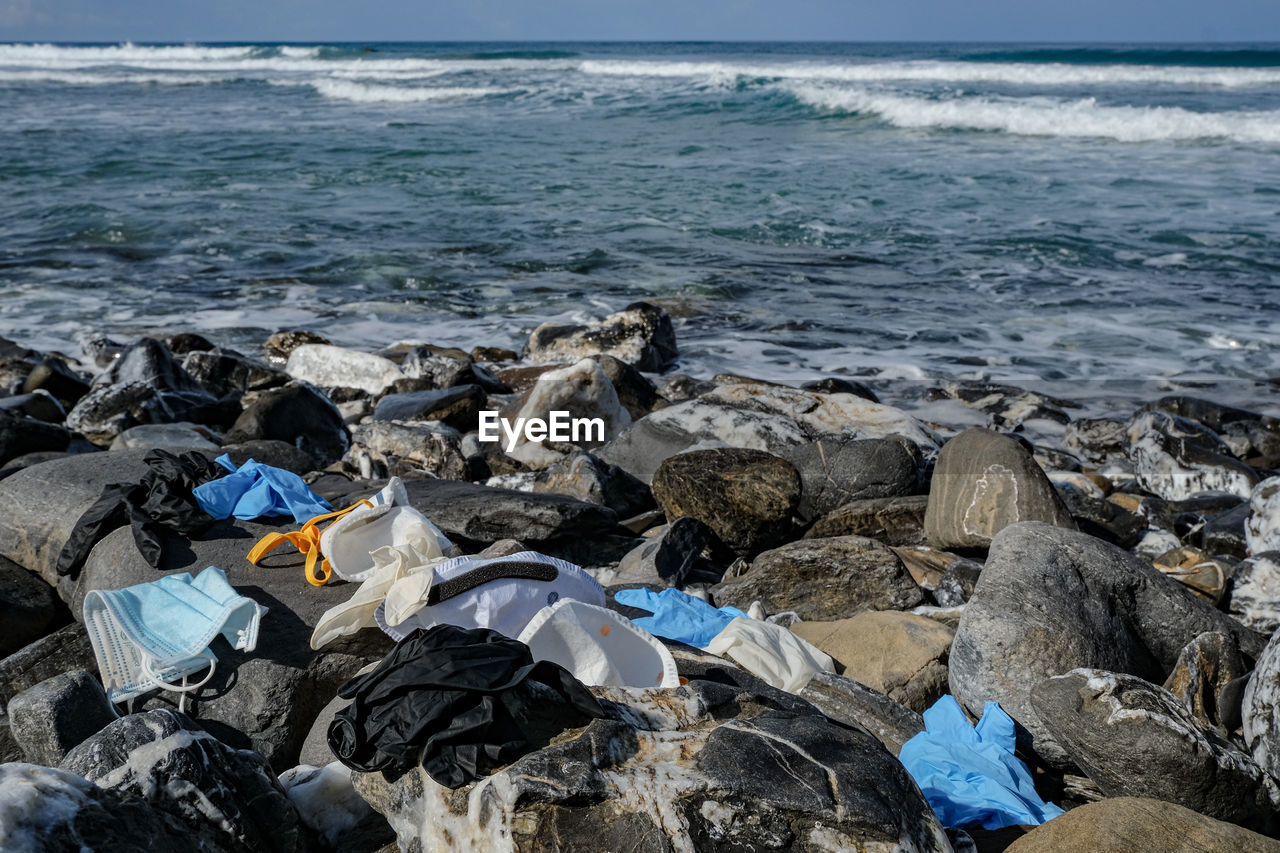 Medical waste,dirty used masks and plastic gloves garbage discarded on sea coast,covid19 pollution