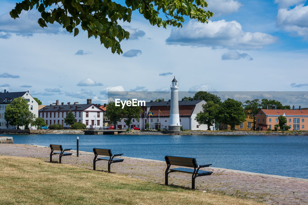View of bench in city against cloudy sky