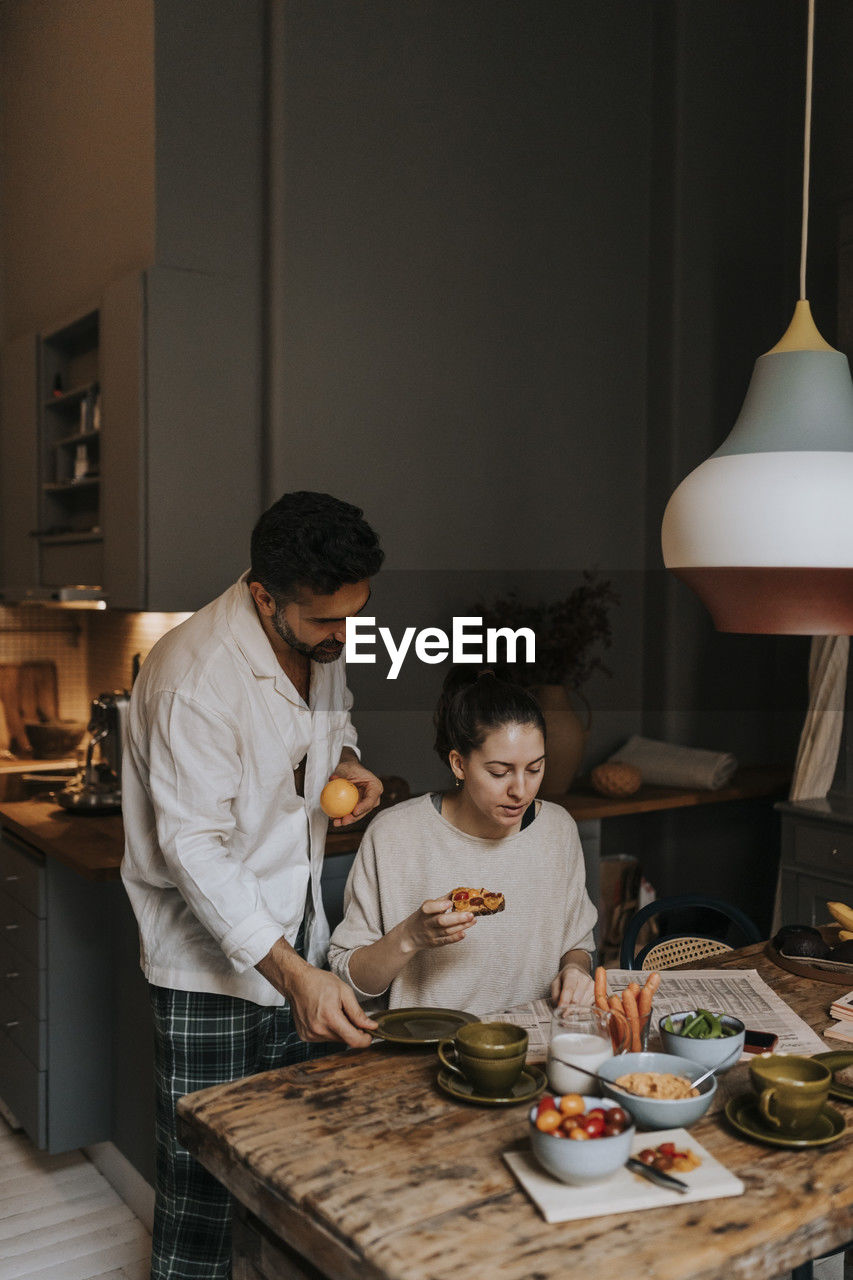 Couple reading newspaper while having breakfast at home