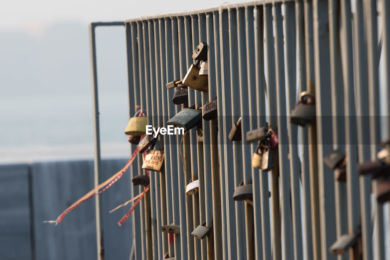 Close-up of padlocks hanging railing against sky