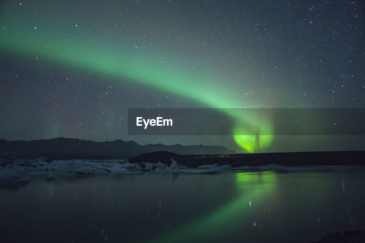 Scenic view of aurora borealis over lake against sky at night