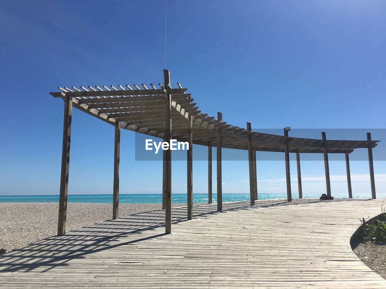 Pier over sea against clear blue sky