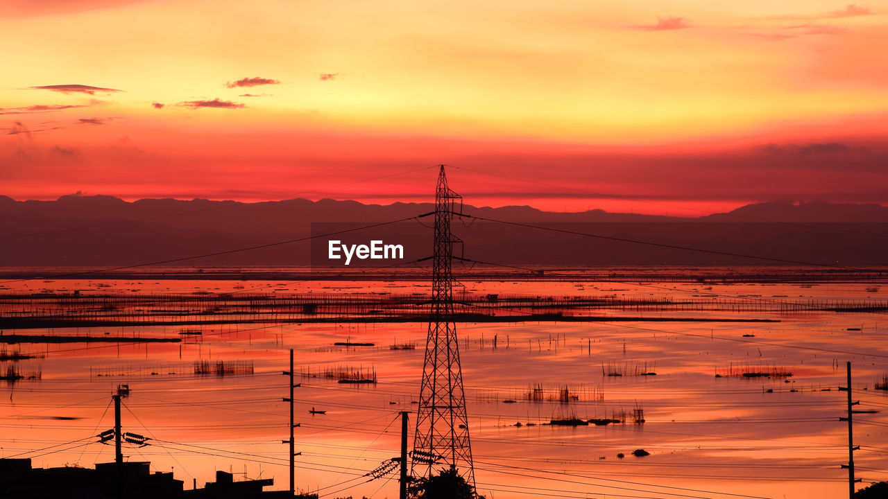 Silhouette electricity pylon against romantic sky at sunrise