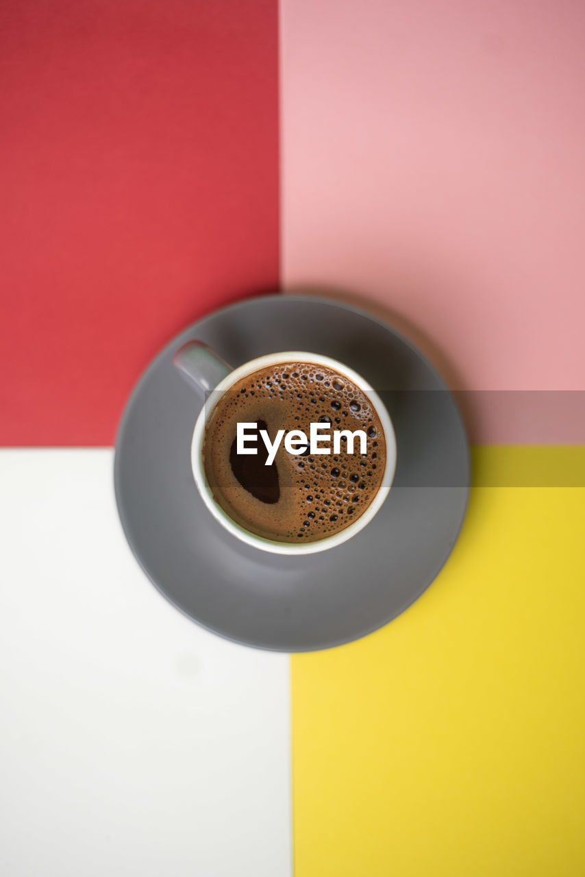 HIGH ANGLE VIEW OF COFFEE CUP ON TABLE AGAINST WALL