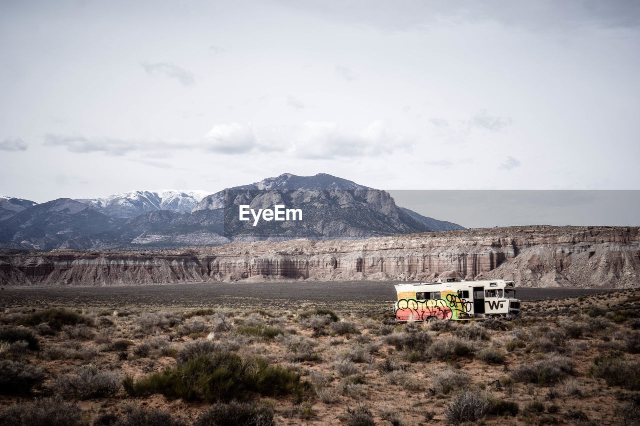 Graffiti van on field by mountains against sky