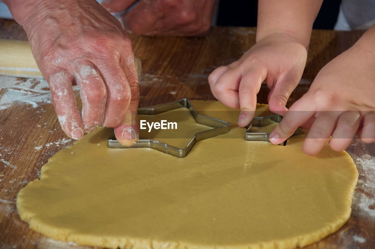 Cropped hands of people preparing cookies on table