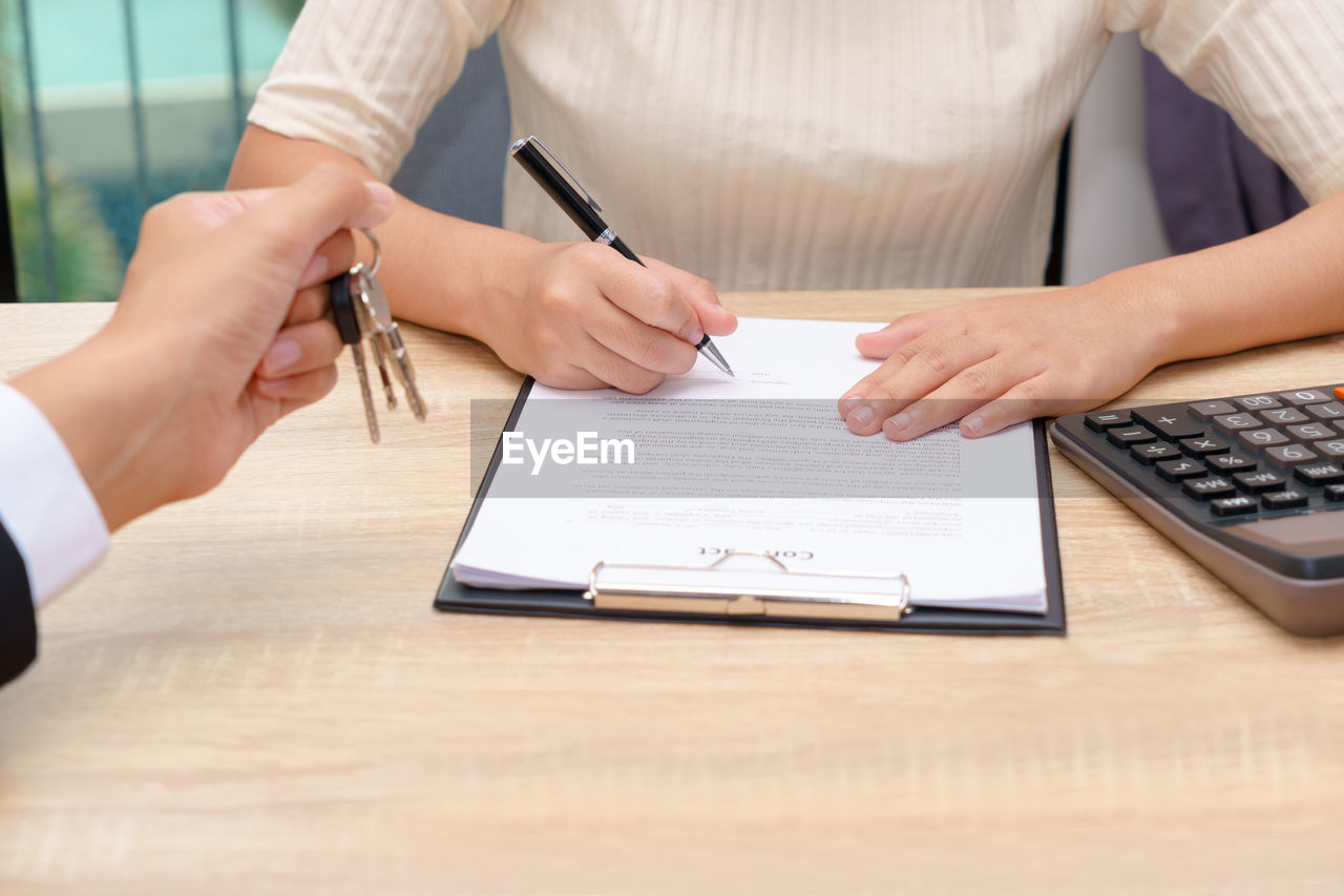 MIDSECTION OF WOMAN HOLDING PAPER WITH HANDS