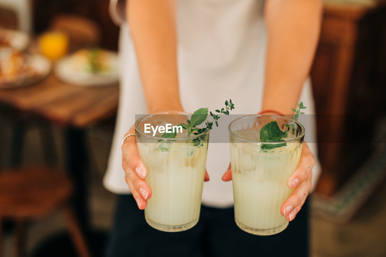 Woman holding non-alcoholic beverage, cold lemonade with mint and ice