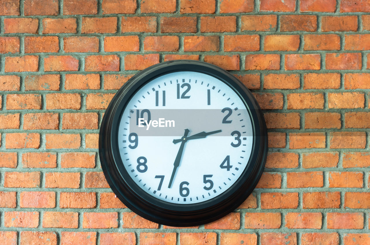 CLOSE-UP OF CLOCK ON BRICK WALL AGAINST STONE WALLS