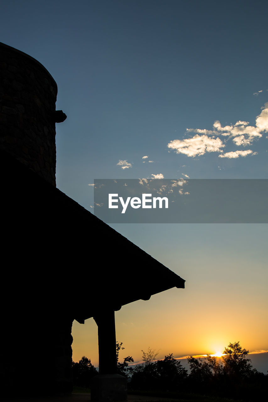 Low angle view of silhouette house against sky at sunset