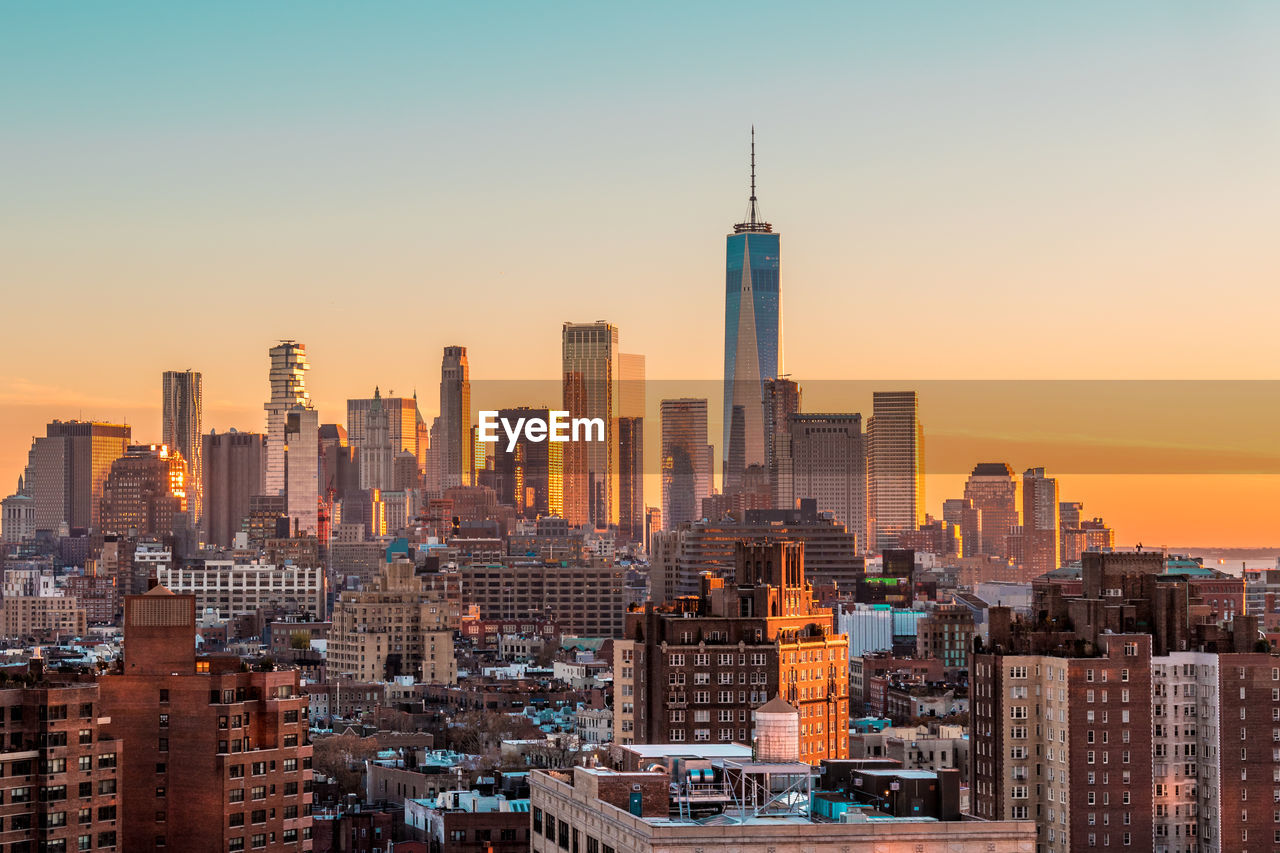 Modern buildings in city against sky during sunset