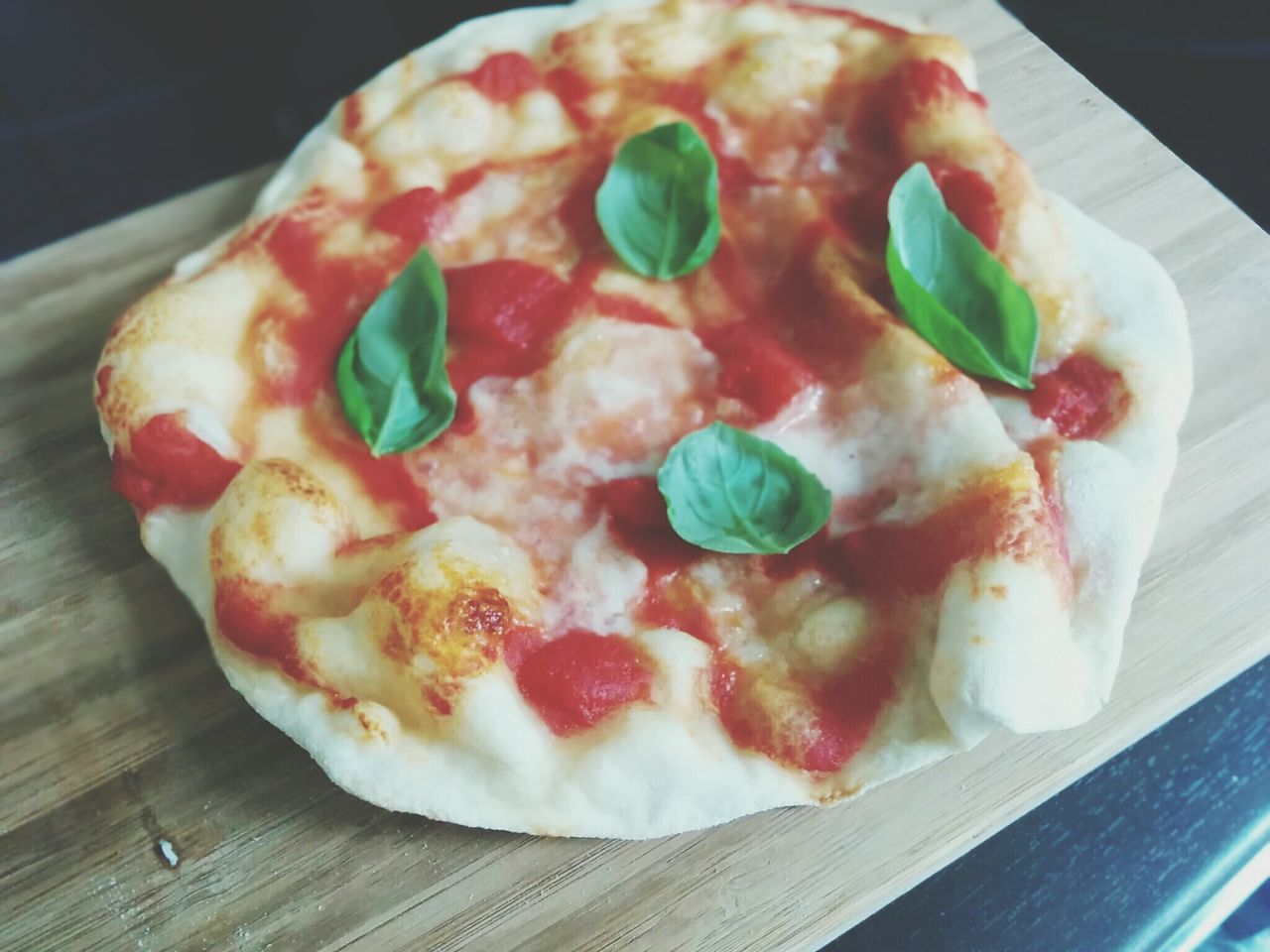 Close-up of pizza bread with tomato sauce topped with herb leaves