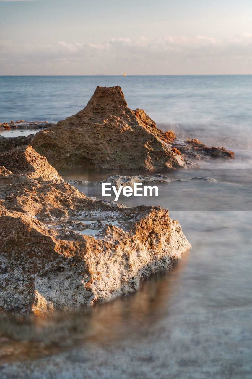 SCENIC VIEW OF ROCKS ON SEA AGAINST SKY