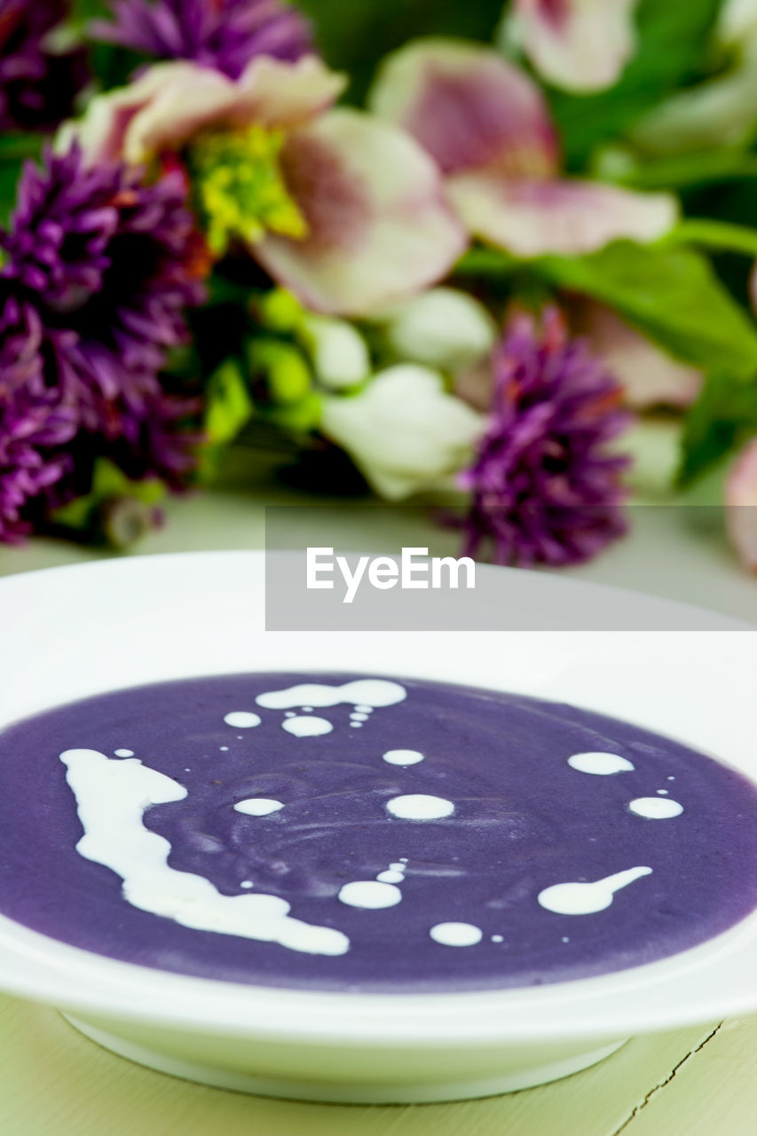 Close-up of soup served in bowl with flowers on table