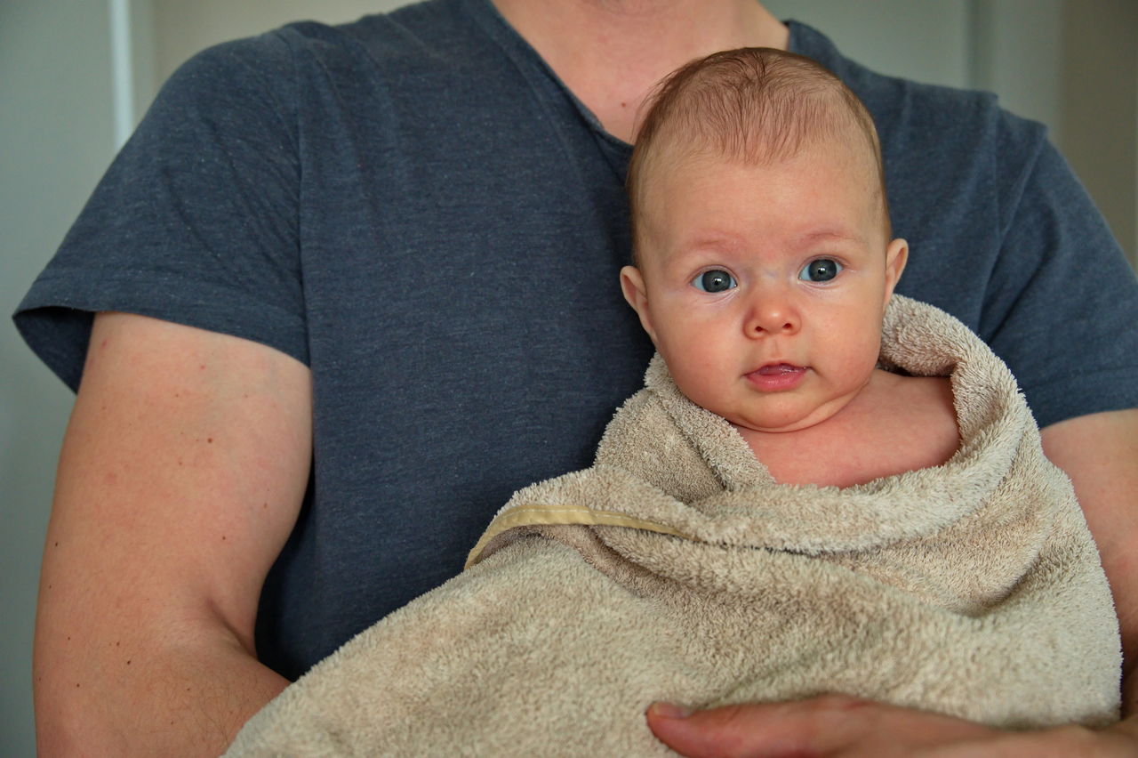 Newborn baby girl in towel after bath held by his father