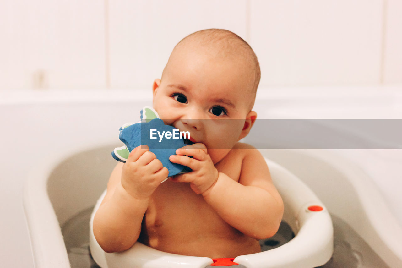 Sweet funny baby taking a bath. baby chewing a toy in a bath chair.