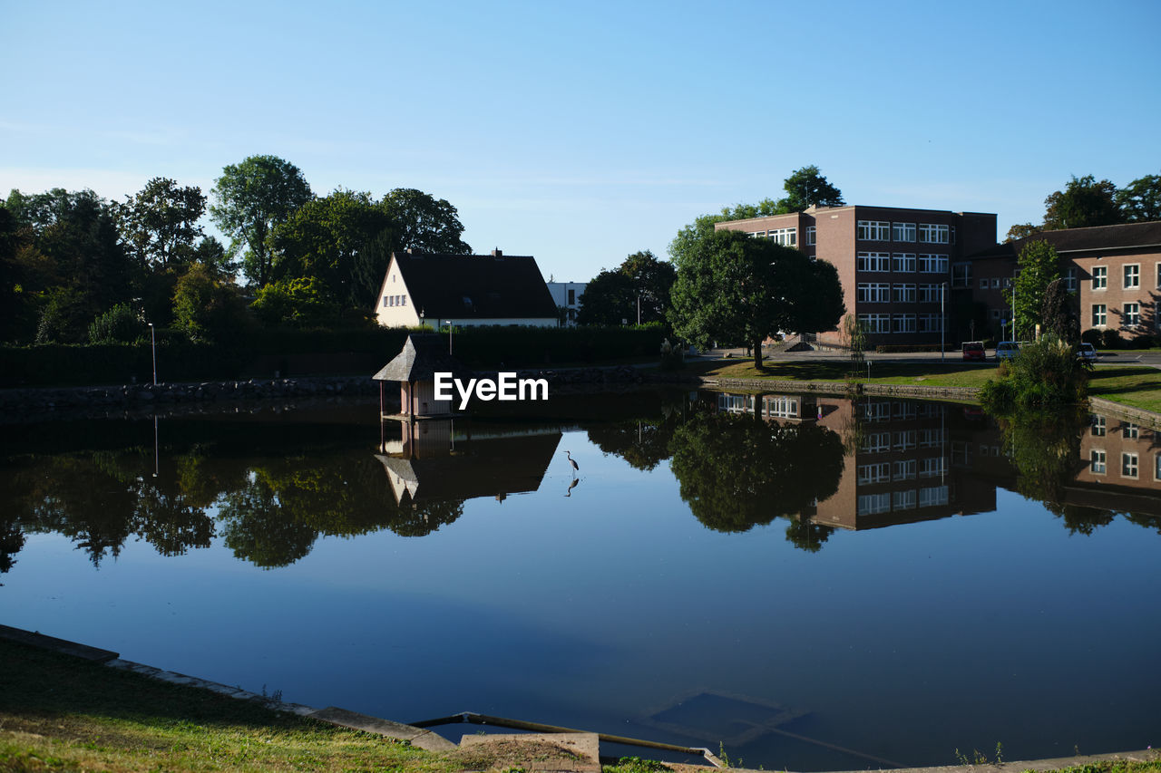 Reflection of building and trees in lake against sky