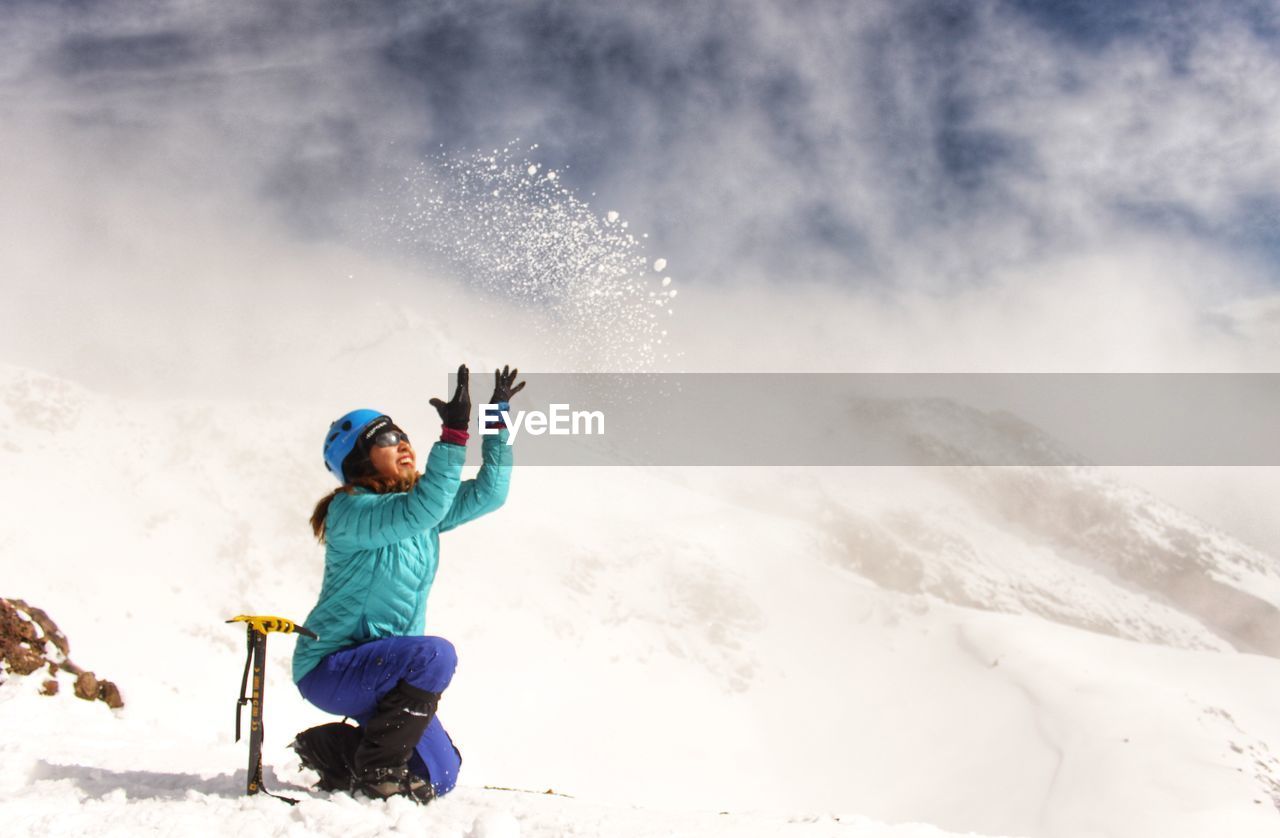 Full length of girl throwing snow mid-air during winter