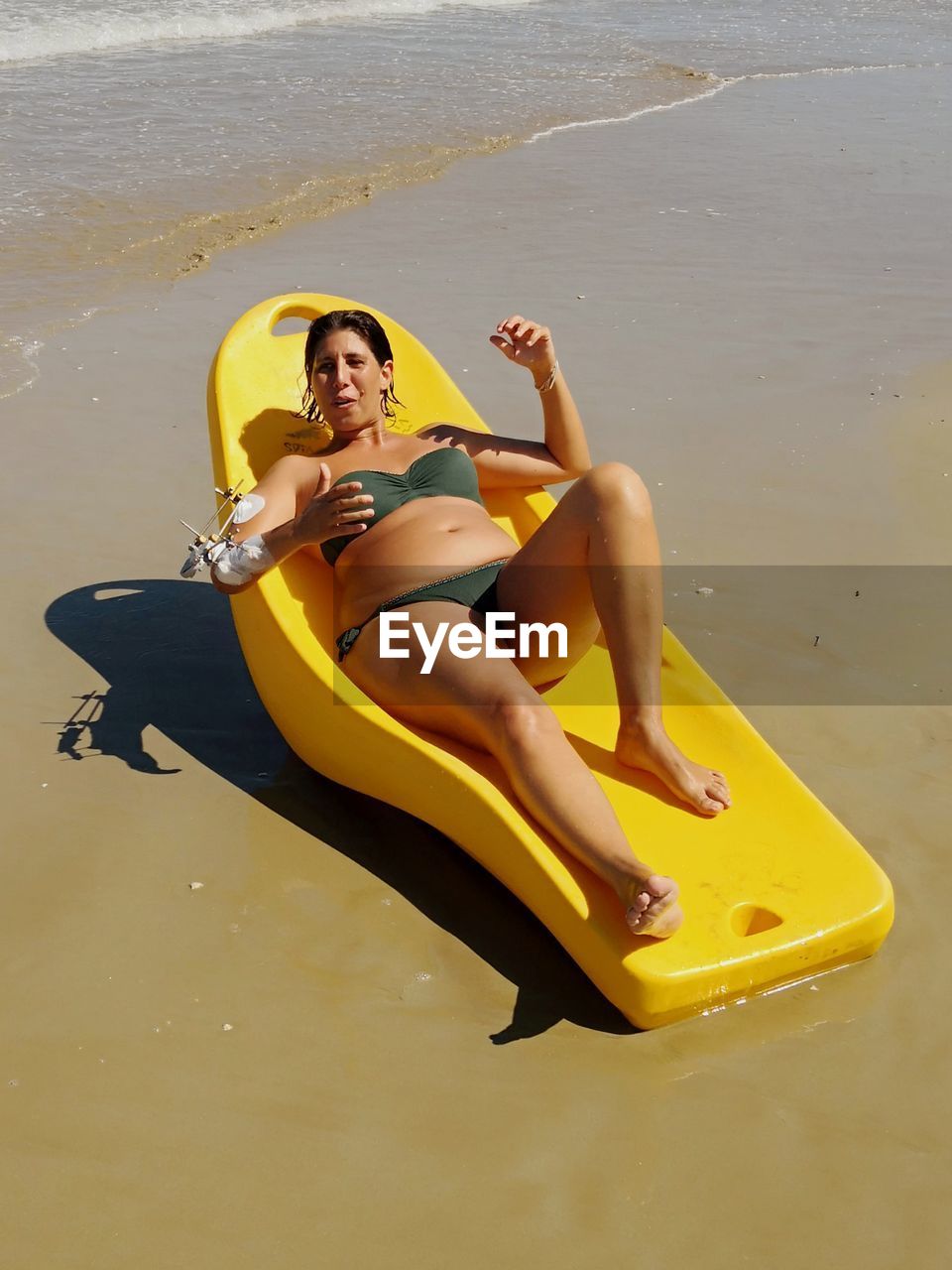 HIGH ANGLE VIEW OF WOMAN SITTING ON SHORE