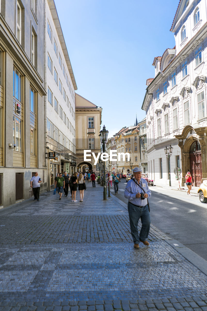 PEOPLE WALKING ON STREET AGAINST BUILDINGS