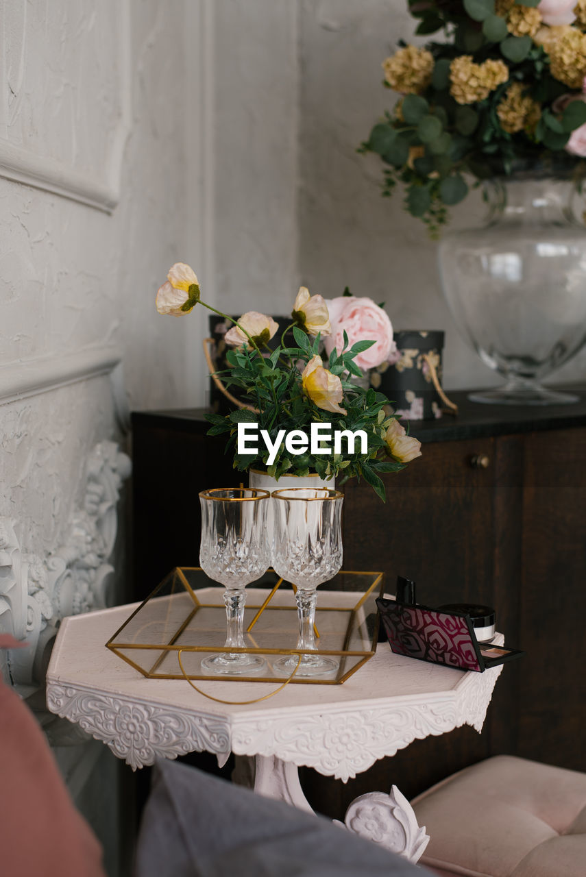Wine glasses and a bouquet of flowers in a vase in the living room as a home decor