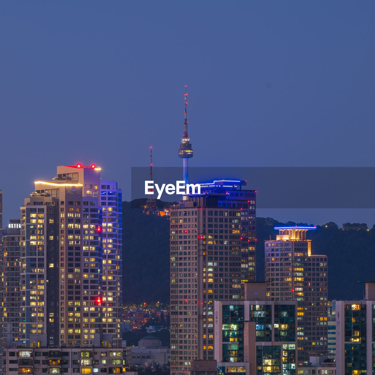 ILLUMINATED BUILDINGS IN CITY AGAINST CLEAR BLUE SKY