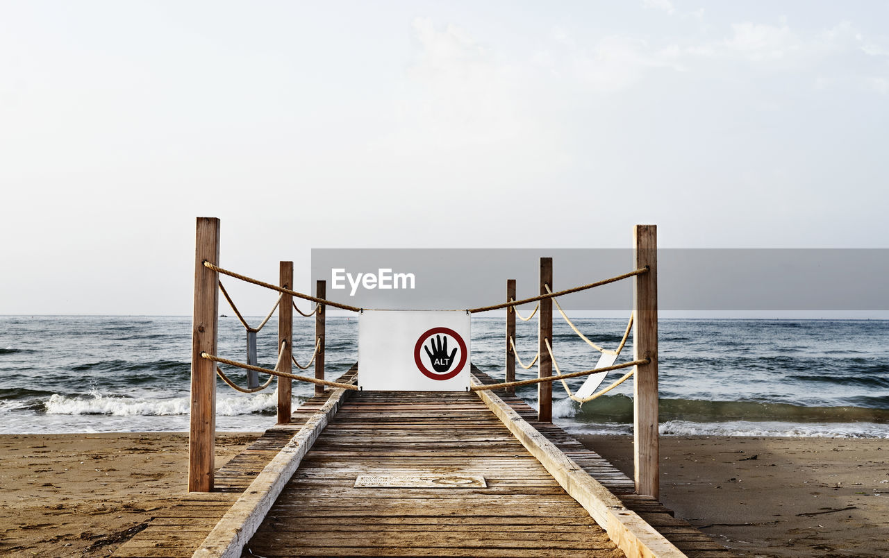 Wooden pier at the sea with danger sign -no access -