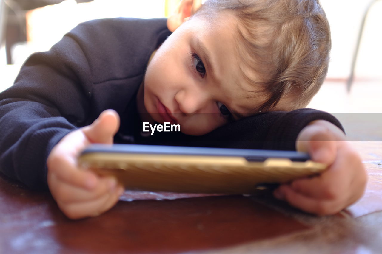 CLOSE-UP PORTRAIT OF BOY USING SMART PHONE