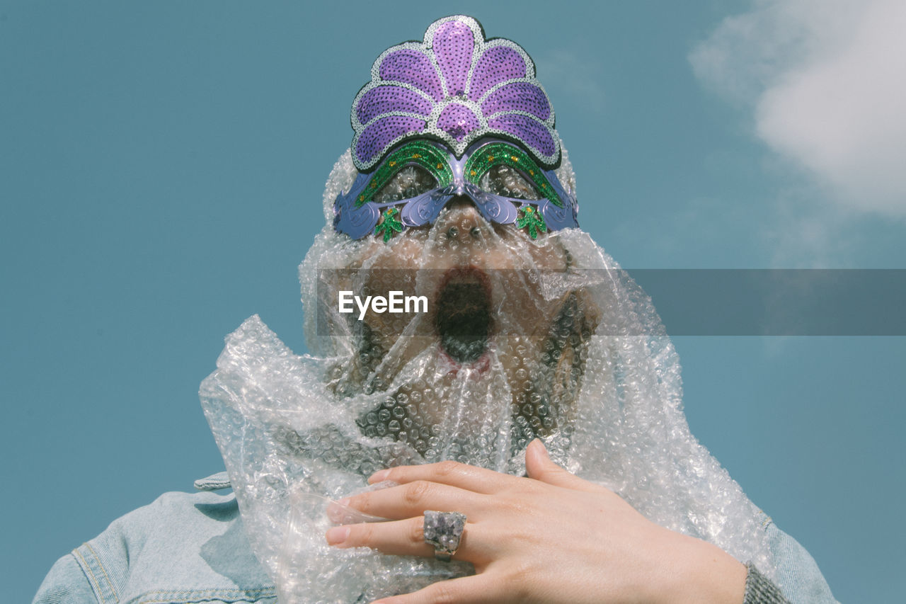 Low angle view of woman wearing eye mask against sky