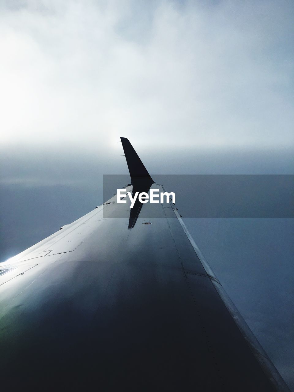 Close-up of airplane flying over sea against sky