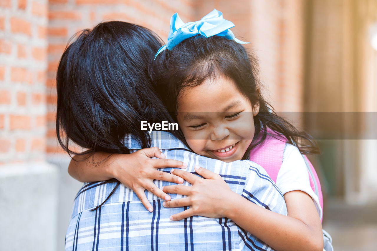 Smiling girl embracing mother outdoors