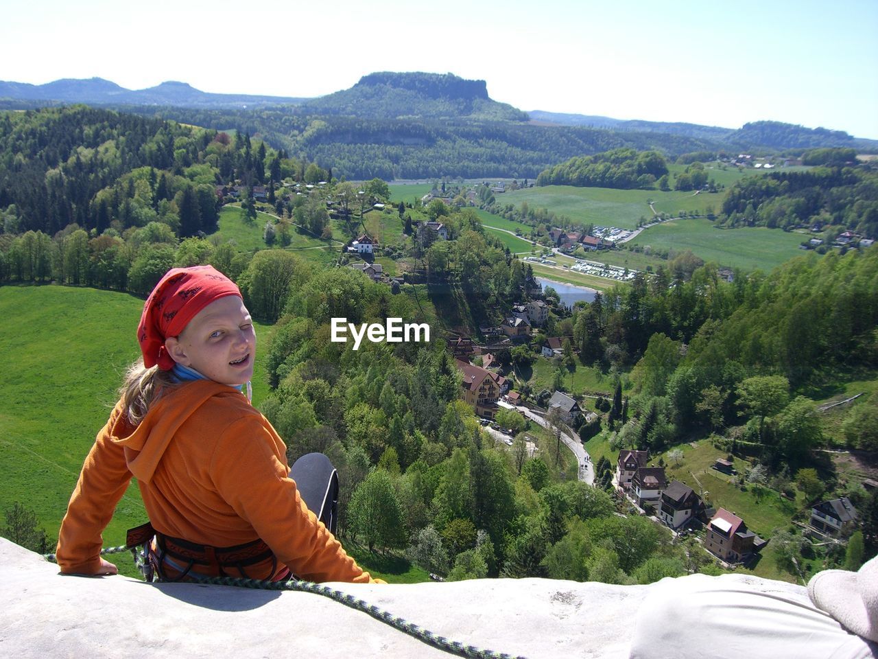 Portrait of female hiker sitting on mountain against sky