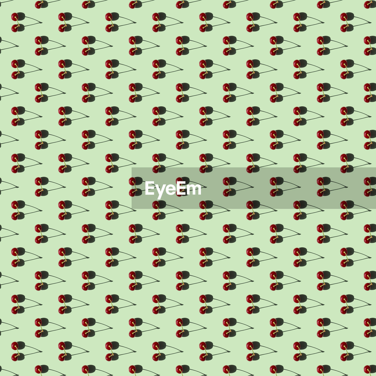 Seamless pattern of two cherries on a green background